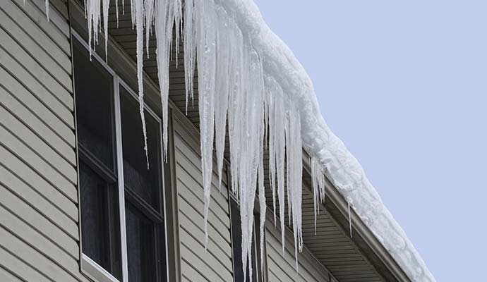 Icicles hanging heavily from the gutter and roofline of a residential building Icicles hanging heavily from the gutter and roofline of a residential building